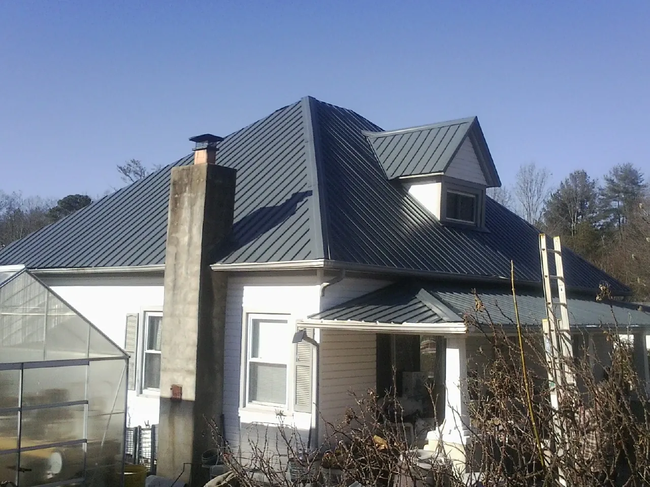 Dark blue standing seam metal roof on a white farmhouse with dormer — Slate & Tile Roof Repair by Roofing Brothers in Camp Sherman