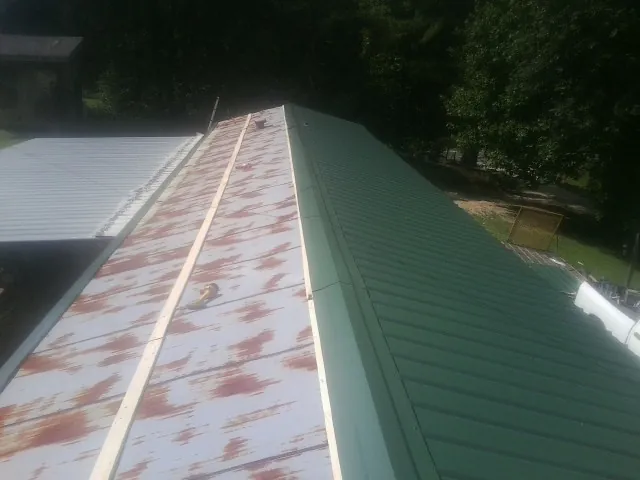 Old rusted panels beside newly installed green metal roofing — Wind Damage Roof Repair by Roofing Brothers in Camp Sherman
