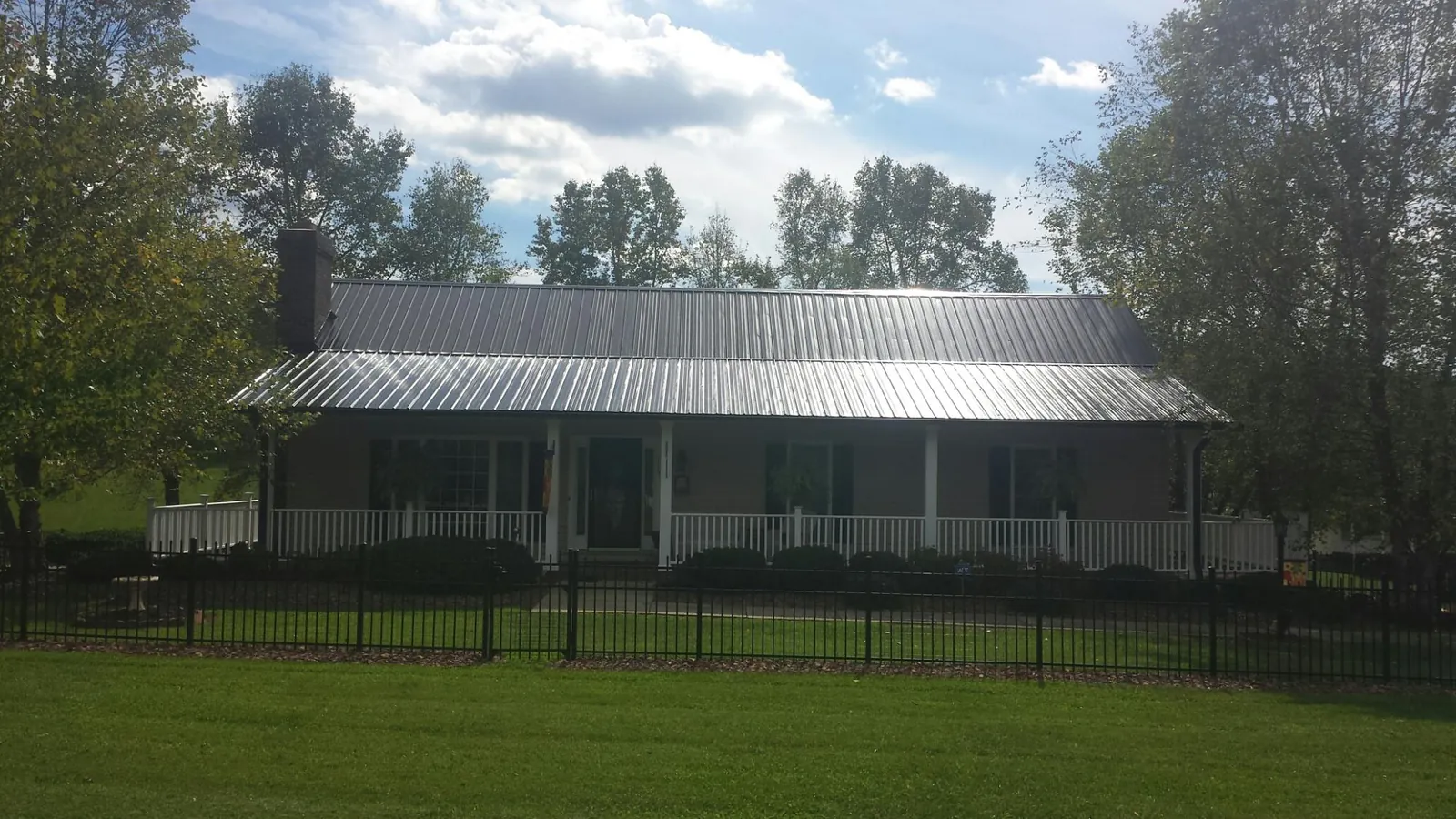 Gray metal roof on a brick ranch with a full width front porch — Gutter Guard Installation work by our crew in Camp Sherman