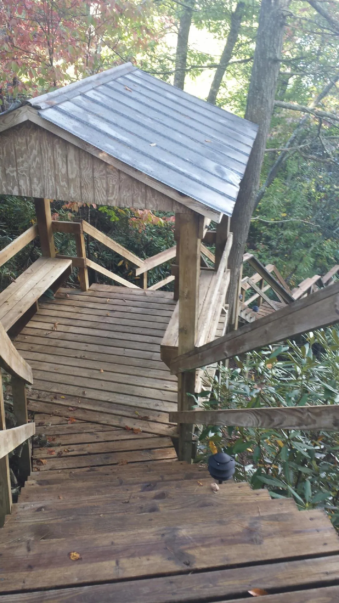 Metal roofed shelter over wooden steps on a wooded walkway — Skylight Repair & Installation work by our crew in Camp Sherman