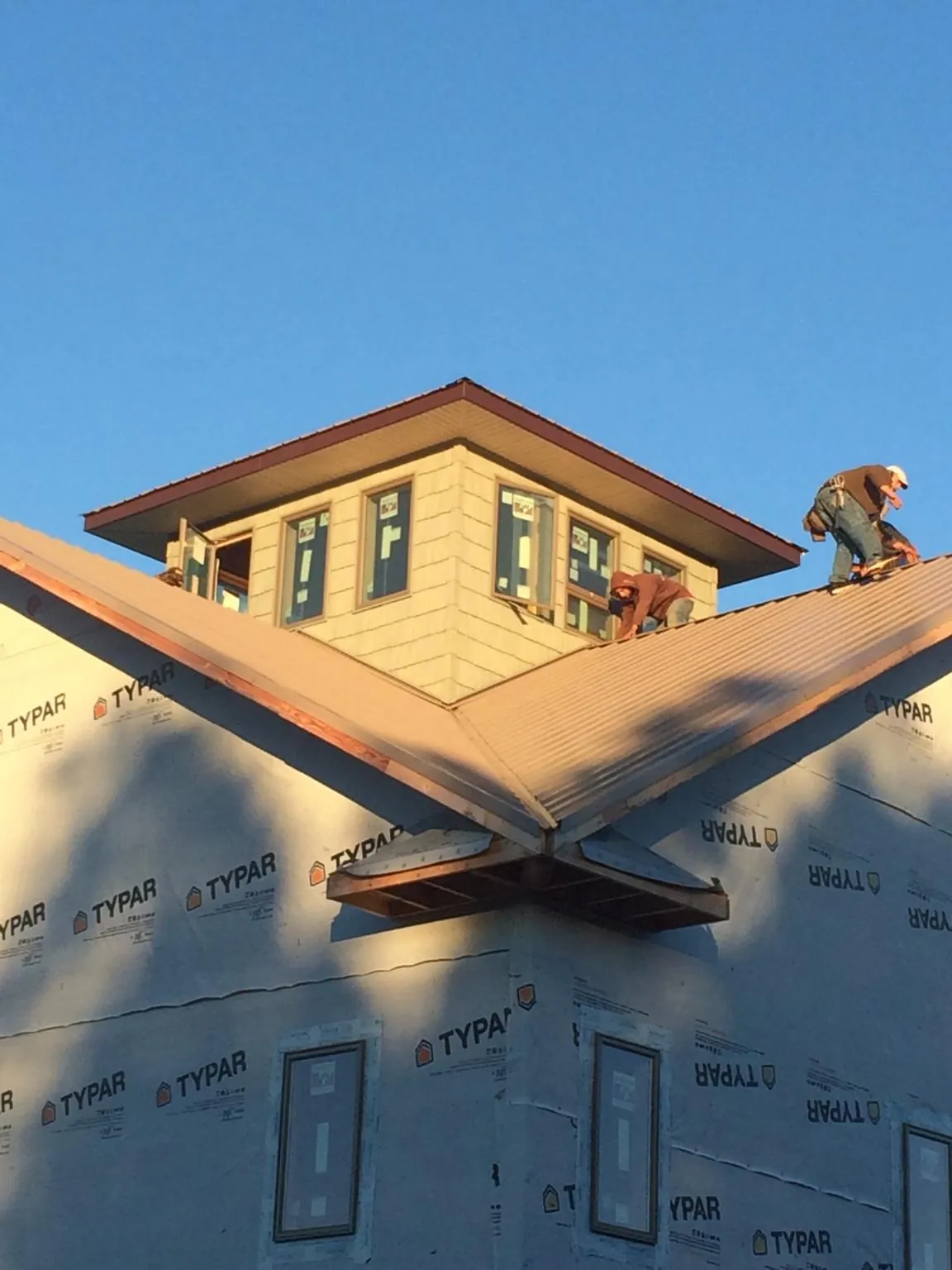 Roofers working around a rooftop cupola on a new metal roof at sunset — Roof Waterproofing in Camp Sherman by Roofing Brothers